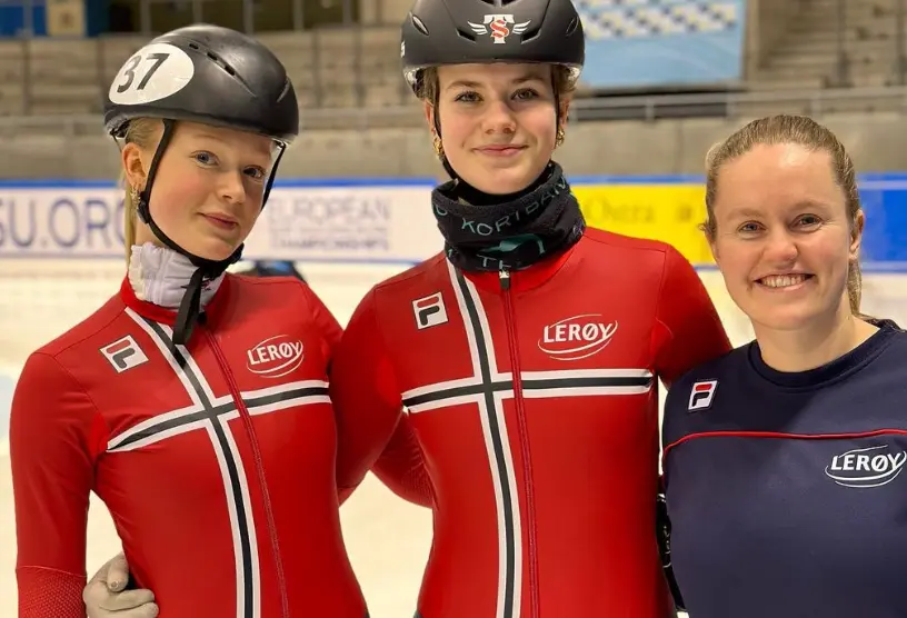 Short track speed skating girls smiling to camera, wearing helmets and skating gear, celebrating a successful training day on the ice.