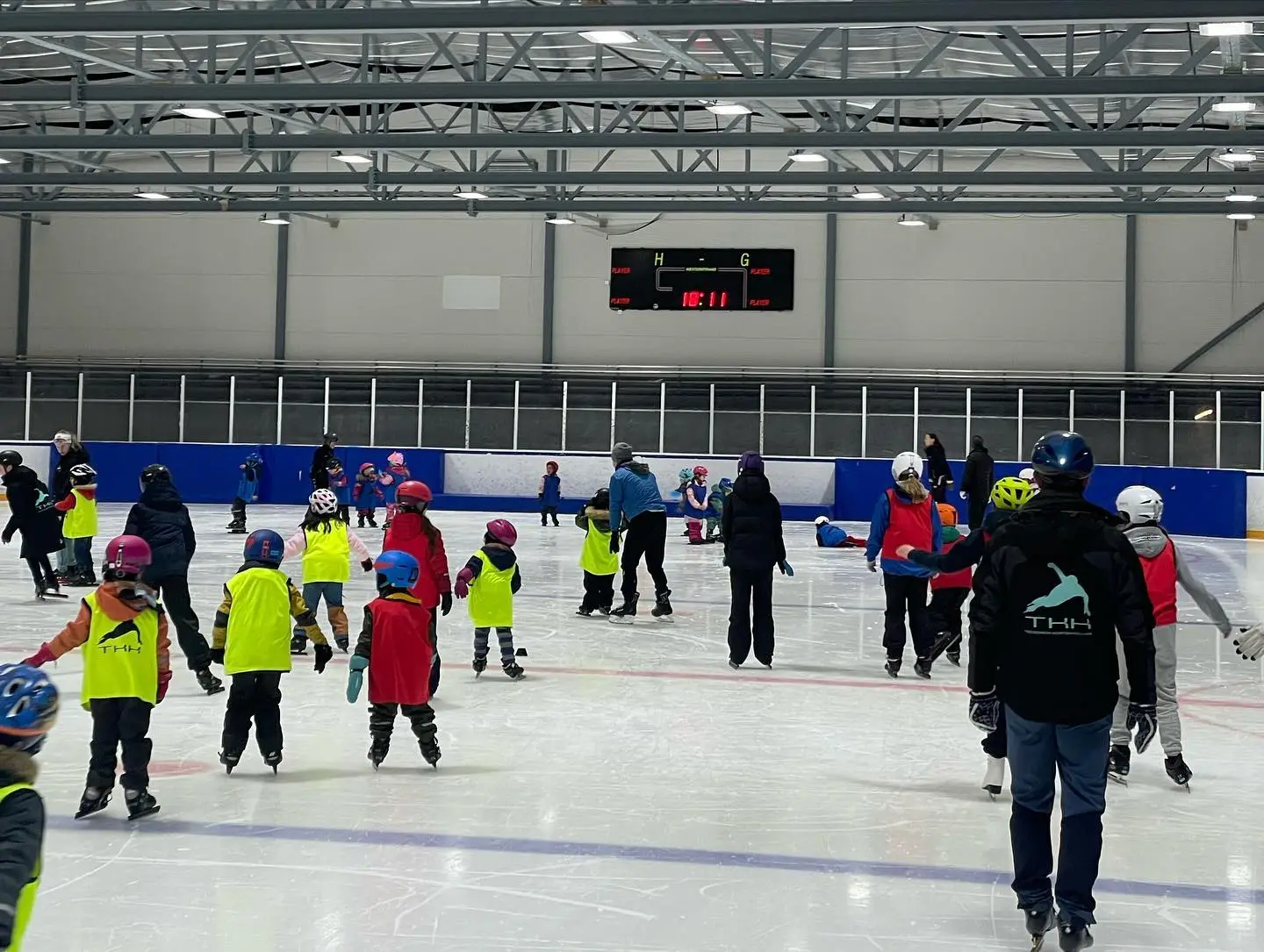 Young athletes practicing at a short track speed skating school, focusing on technique and speed on an indoor ice rink.